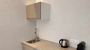 Moderni keittiö, jossa on integroitu pesuallas, vedenkeitin ja kahvinkeitin työtasolla.