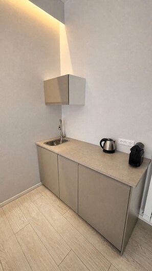 A modern kitchen with a built-in sink, a kettle, and a coffee maker on the countertop.