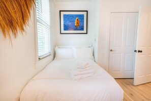 A bedroom with a bed, a framed picture on the wall, a door, and a window with blinds. - Walk to King St | Spacious Charleston Stay (Charleston)