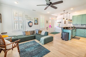 A modern living room with a sectional sofa, a dining area, and a kitchen with teal cabinets. - Walk to King St | Spacious Charleston Stay (Charleston)