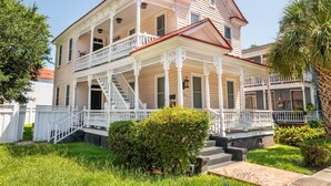 Ein zweistöckiges Haus mit Veranda, Treppe und einem gepflegten Garten.