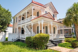A two-story house with a porch, a staircase, and a well-maintained garden. - Walk to King St | Spacious Charleston Stay (Charleston)