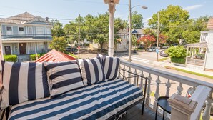 Ein Balkon mit einem Bett, einer Geländer und Blick auf die Nachbarschaft.