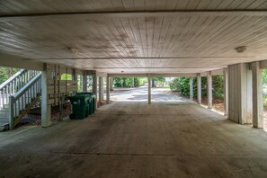 Ein leerer überdachter Außenbereich mit Betonboden, Holzsäulen und einer Treppe auf der linken Seite.