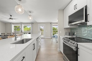 A modern kitchen with a central island, built-in oven, and pendant lighting. - Mollymawk Cottage: Peaceful Pool Home Near Beaches, Golf & Island Adventures (Sanibel)