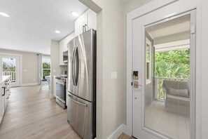 A modern kitchen with a stainless steel refrigerator, an oven, and a dining area with a table and chairs. - Mollymawk Cottage: Peaceful Pool Home Near Beaches, Golf & Island Adventures (Sanibel)