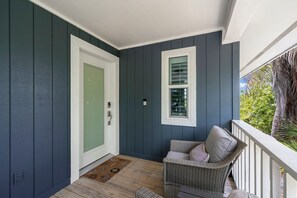 A porch with a wicker chair, a door, and a window. - Mollymawk Cottage: Peaceful Pool Home Near Beaches, Golf & Island Adventures (Sanibel)