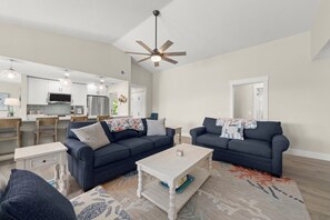 A modern living room with two dark sofas, a coffee table, and a patterned rug. - Mollymawk Cottage: Peaceful Pool Home Near Beaches, Golf & Island Adventures (Sanibel)