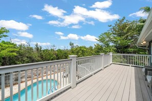 A wooden deck with a pool, surrounded by lush greenery and a clear sky. - Mollymawk Cottage: Peaceful Pool Home Near Beaches, Golf & Island Adventures (Sanibel)