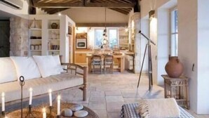 A rustic interior with a stone floor, wooden beams, a sofa, a dining area, and a large vase. - Aphrodite's Oasis with Private Pool (Pomos)
