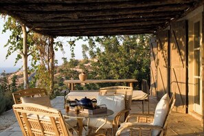 An outdoor seating area with wicker furniture and a table, overlooking a scenic landscape. - Aphrodite's Oasis with Private Pool (Pomos)