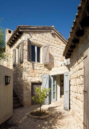 A stone building with a small garden, a staircase, and a door. - Aphrodite's Oasis with Private Pool (Pomos)