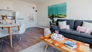 A modern living space with a dining area, a sofa set, and a kitchen. - 5-7 Harold St Middle (Middle Park)