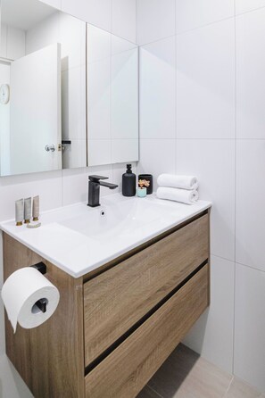 A modern bathroom with a white sink, wooden vanity, and a mirror above. - 5-7 Harold St Middle (Middle Park)