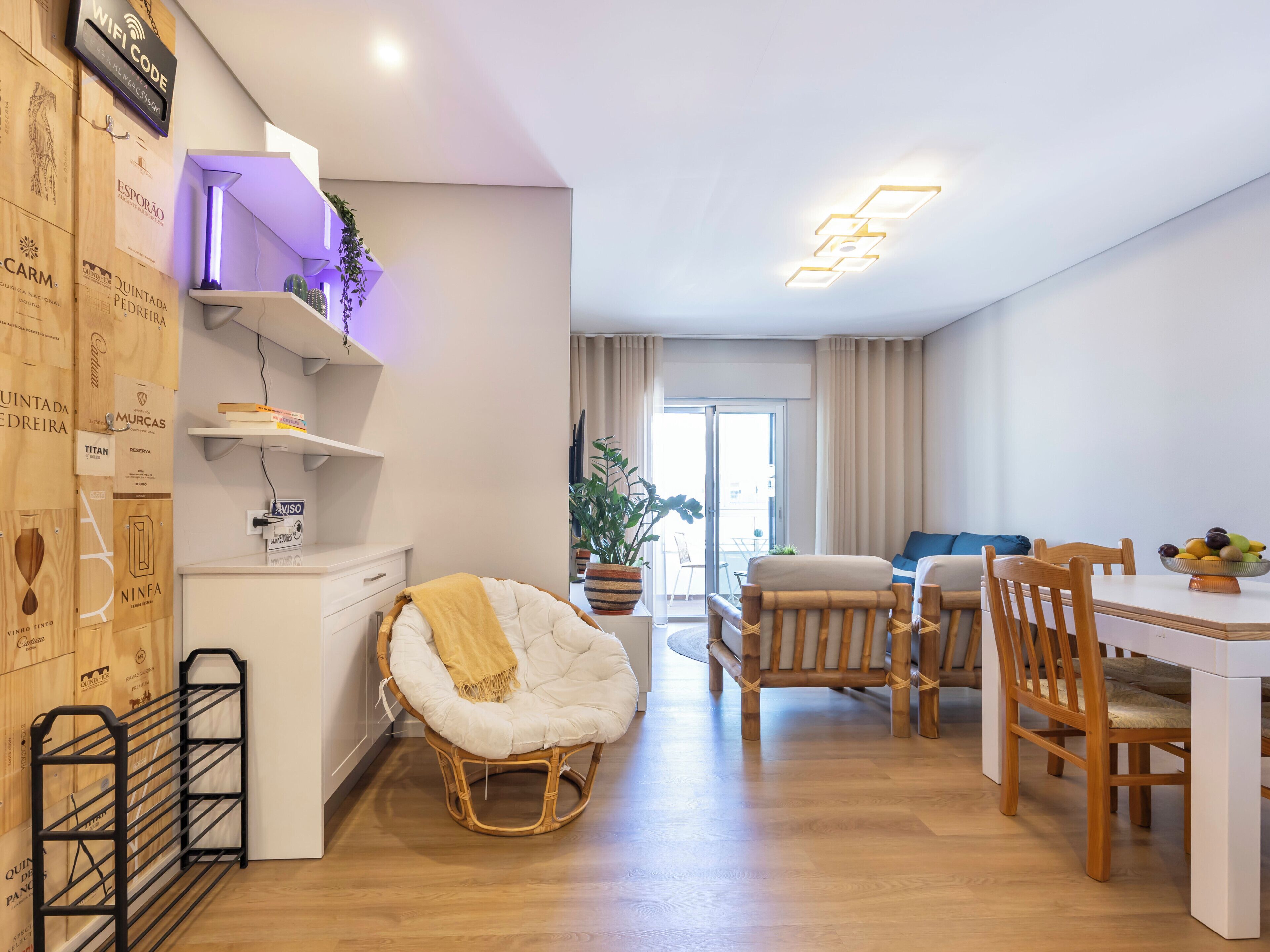 A modern living room with a dining area, wooden furniture, a white sofa, and a wicker chair.