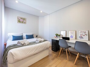 Une chambre moderne avec un lit, des tables de chevet, un bureau et des chaises.