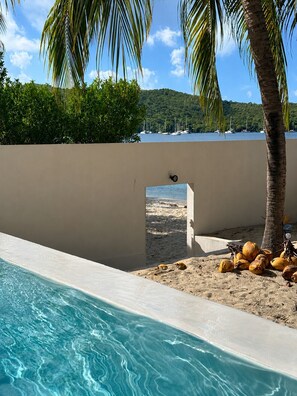 A swimming pool with a clear view of the beach and boats in the background. - Dream Villa in Martinique, with a Pool and Direct Access to the Beach (Les Anses-d'Arlet)