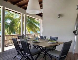 An outdoor dining area with a wooden table set for four, surrounded by chairs, under a white ceiling light. - Dream Villa in Martinique, with a Pool and Direct Access to the Beach (Les Anses-d'Arlet)