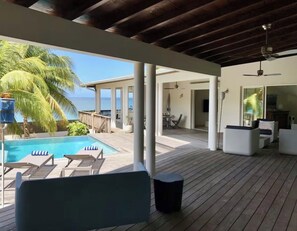 A covered outdoor area with a pool, lounge chairs, and a view of the ocean. - Dream Villa in Martinique, with a Pool and Direct Access to the Beach (Les Anses-d'Arlet)