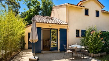 A two-story house with a patio area, outdoor furniture, and a garden.