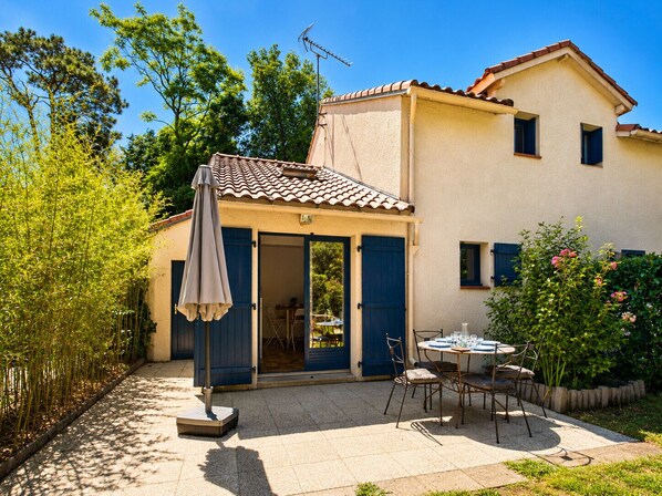 A two-story house with a patio area, outdoor furniture, and a garden.