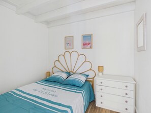 A bedroom with a bed, a nightstand, a dresser, and two wall-mounted pictures.
