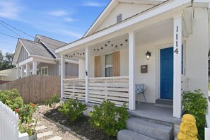 A residential house with a porch, a blue door, and a small garden area.
