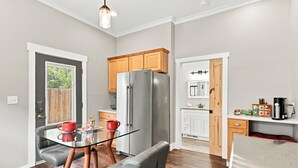 Una cocina moderna con mesa de comedor de vidrio, refrigerador, armarios de madera y horno empotrado.