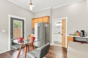 A modern kitchen with a glass dining table, a refrigerator, wooden cabinets, and a built-in oven. - NEW!  Muse on 10th - We Love Doggies! (Wilmington)