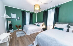 Ein Hotelzimmer mit zwei Betten, einem Spiegel, einer Lampe und einer hängenden Pflanze.