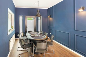 A conference room with a round table, six chairs, and a hanging light fixture.