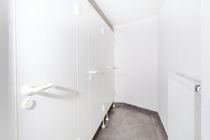 A hallway with white walls, a door with a handle, and a radiator on the right.