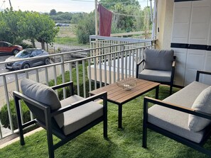 A balcony with a table and two chairs, a view of the street, and a red cloth hanging. - Seaside apartment, air-conditioned (Salou)