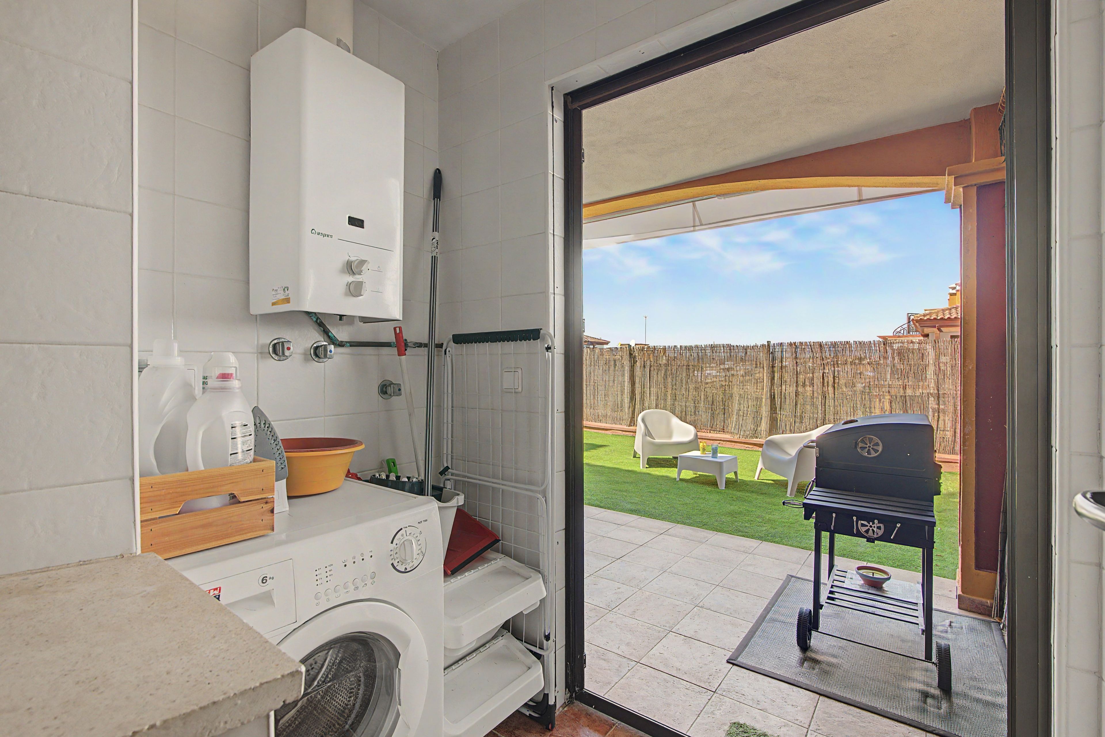 Een wasruimte met een wasmachine, een droogrek en een boiler.