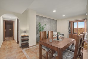 Un comedor con mesa de madera, sillas y vistas al exterior.