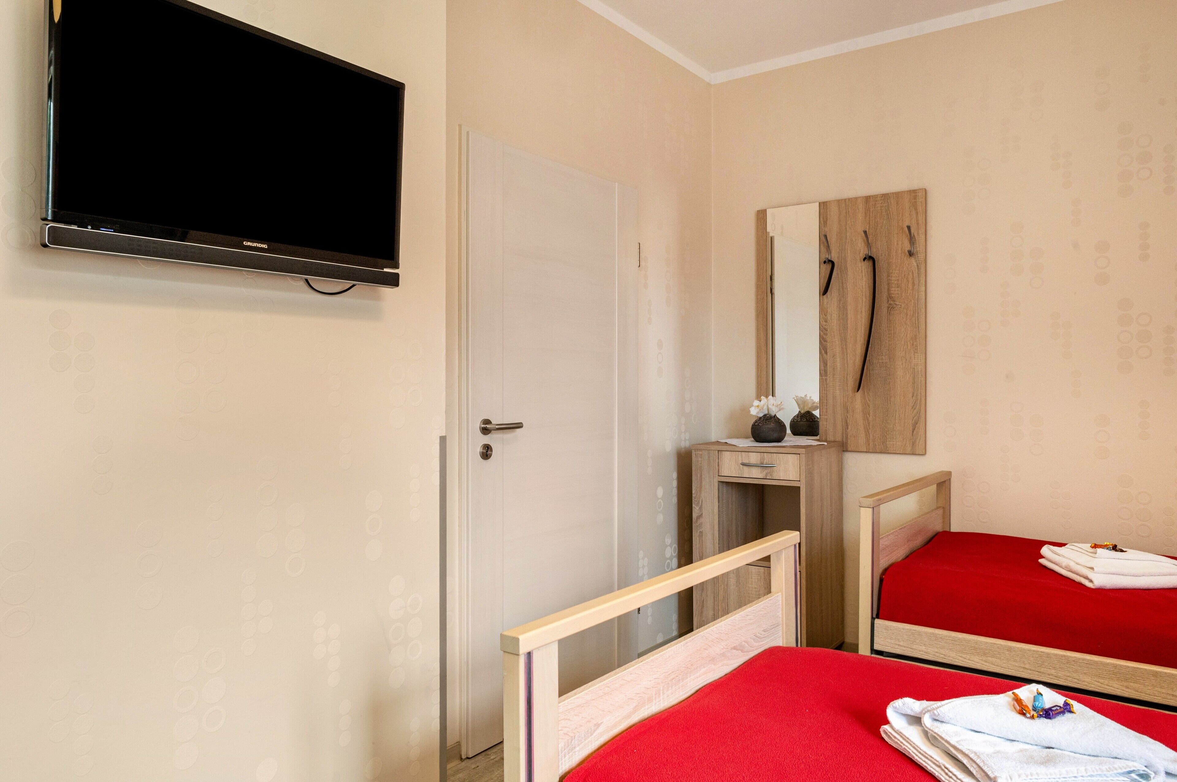 Ein Hotelzimmer mit einem Bett, einem Nachttisch, einem Spiegel und einem an der Wand befestigten Fernseher.