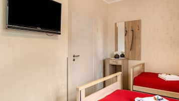 Ein Hotelzimmer mit einem Bett, einem Nachttisch, einem Spiegel und einem an der Wand befestigten Fernseher.