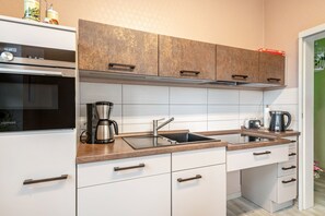 A modern kitchen with white cabinets, a stainless steel sink, and a coffee maker.
