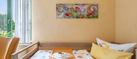 Habitación de hotel con cama, una silla, un cuadro y vista a zonas verdes.