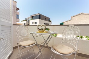 A balcony with two chairs and a small table, a heart-shaped decoration, and a potted plant. - Beach Nest (Split)