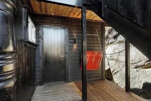 Una puerta de madera con manija metálica, una escalera de madera y una pared de piedra.
