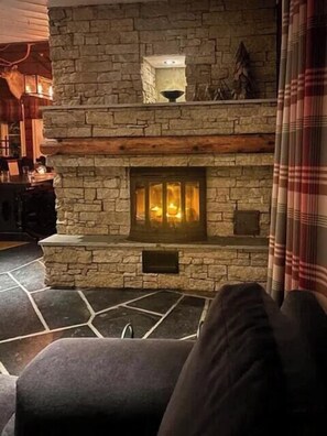 A stone fireplace with a glass door, a wooden mantel, and a stone floor.