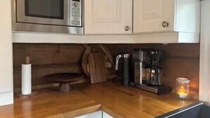 Een keuken met een magnetron, koffiezetapparaat en een pak keukenpapier.
