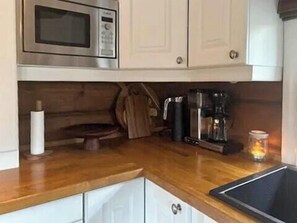 Una cocina con microondas, cafetera y un rollo de toallas de papel.