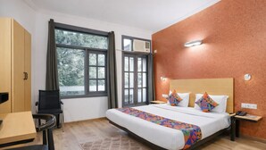 Habitación de hotel con cama, escritorio, silla, ventana y aire acondicionado instalado en la pared.