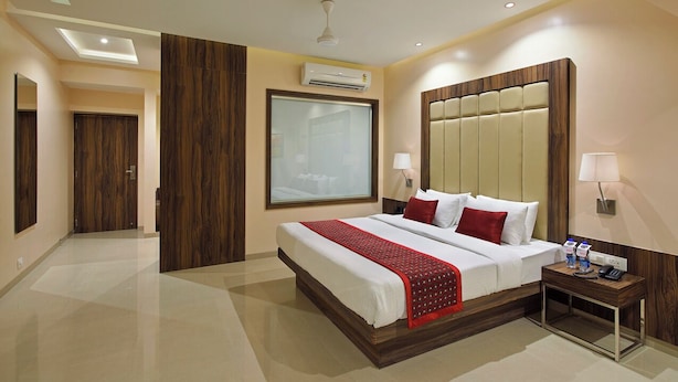 Habitación de hotel con una cama grande, una mesita de noche con lámpara, un equipo de aire acondicionado y un ventilador de techo.