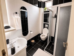 A modern bathroom with a white sink, a toilet, and a shower enclosure. - Kampüs Apart Otel (ANTALYA)