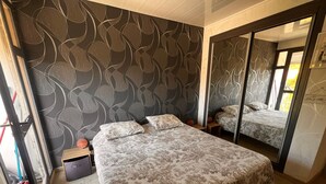 Ein Schlafzimmer mit einem Bett, einem Nachttisch, einem Spiegel und einem Kleiderschrank.