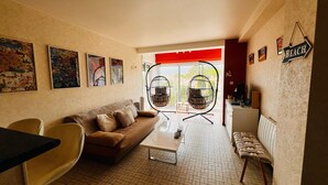 Ein Wohnzimmer mit einer Couch, Sesseln, einem Couchtisch und einem Hängekorbstuhl.