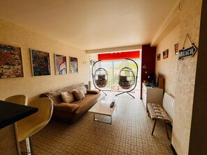 A living room with a sofa, chairs, a coffee table, and a hanging chair. - 3-room apartment near the beach - 57m² (Argelès-sur-Mer)